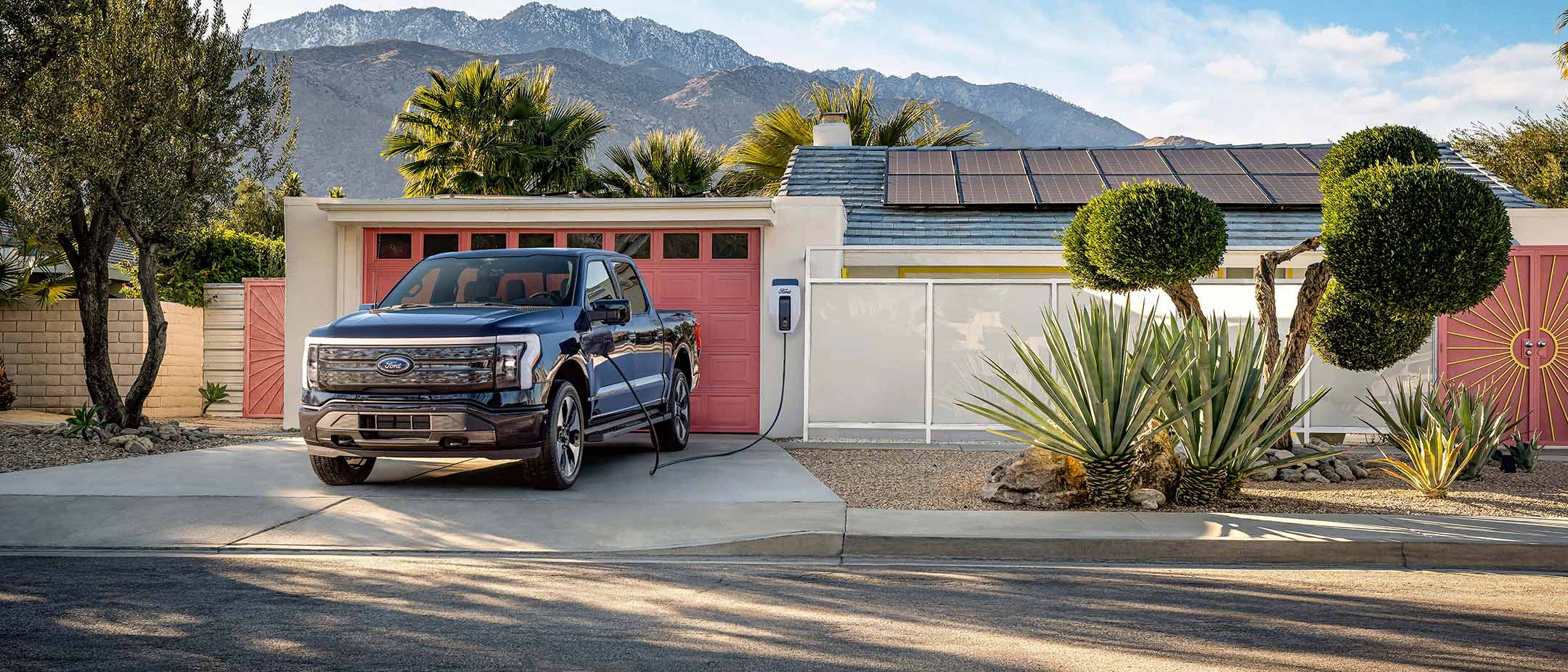 An F-150 Lightning charges in a driveway in the daytime