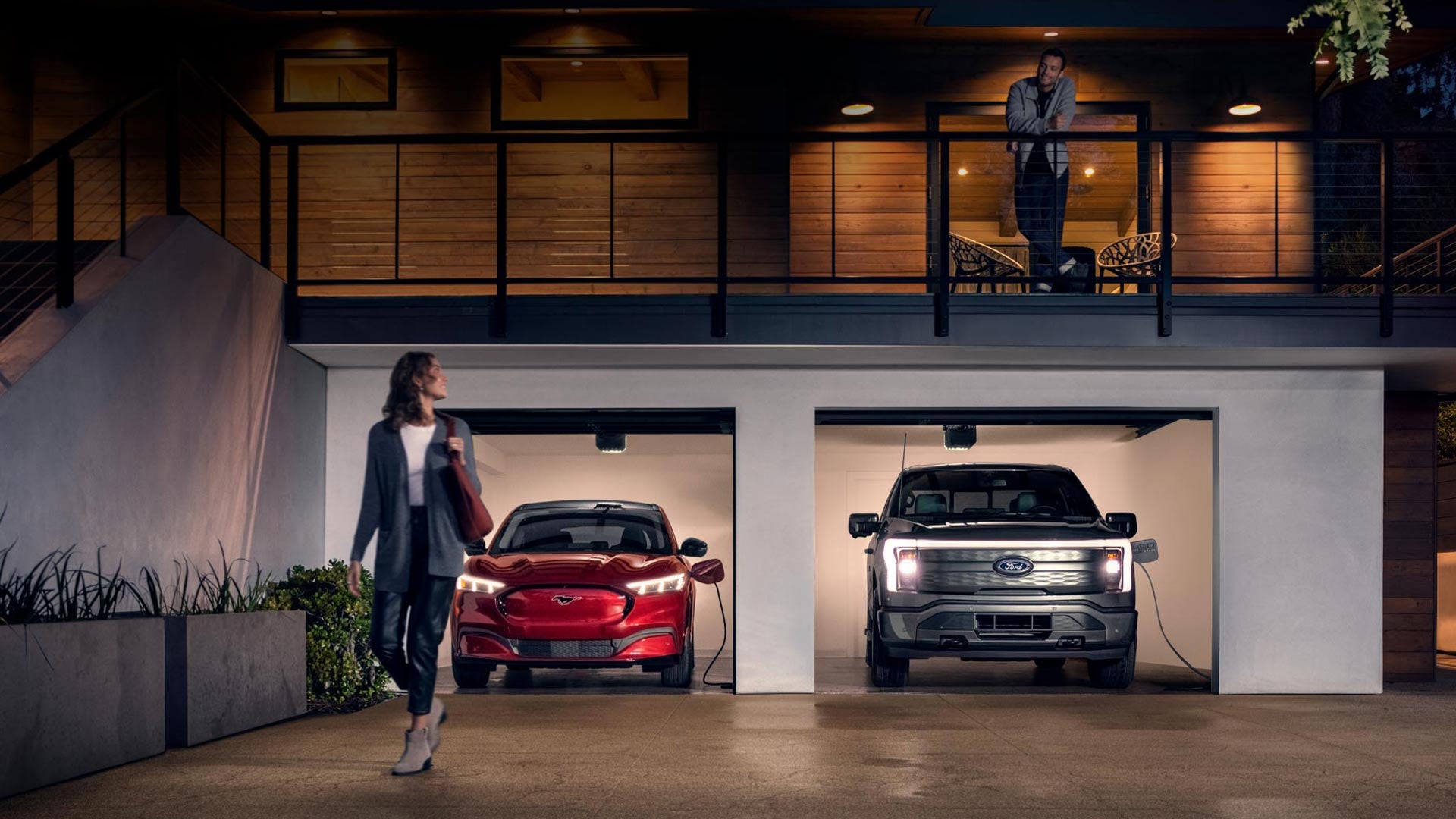 Woman walking out from home garage with a 2024 Mustang® Mach-E and Ford Lightning® truck in plugged-in and charging | Pat Milliken Ford in Redford MI