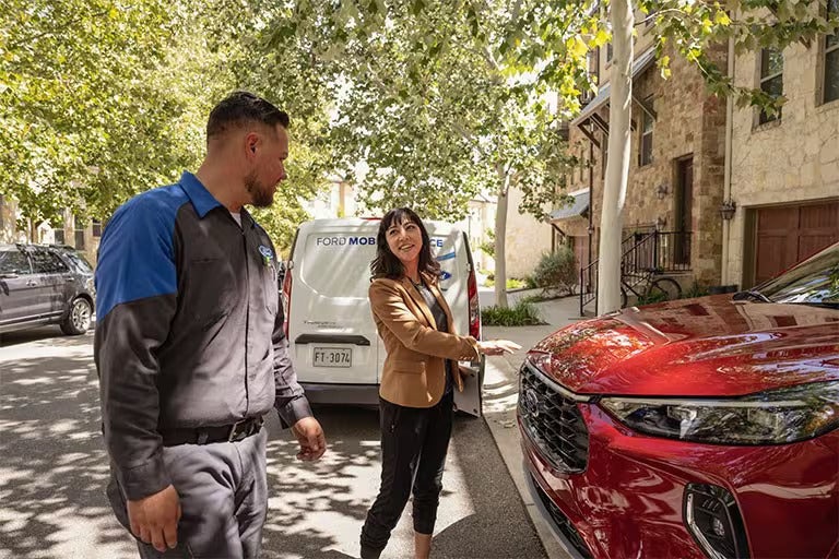 Exterior shot of man in front of house with a white Explorer® SUV cell phone in hand