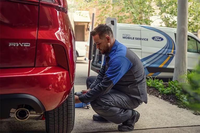 Ford Mobile Service Technician is talking to a woman in front of a Ford vehicle.